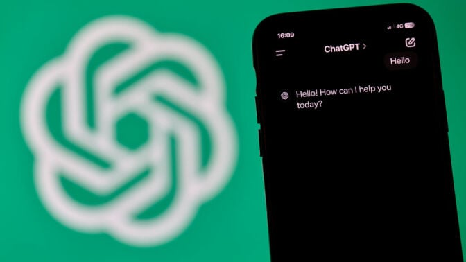 A close-up shot of an iPhone displays the new advanced voice interface of ChatGPT, with an iMac in the background showing the ChatGPT icon on screen